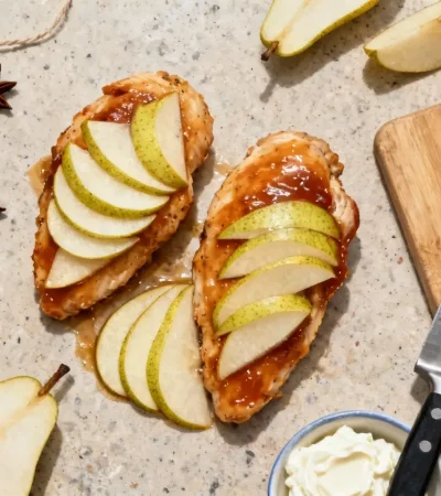 Filets de poulet nappés de glaçage avec écailles de poire disposées en motif, accompagnés de badiane et ingrédients sur plan de travail