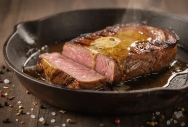 Steak medium-rare parfaitement saisi dans poêle en fonte